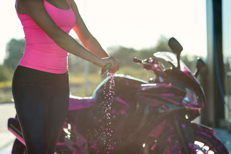 Close up womans hands squeeze moisture out of the rag while wipes sport motorcycle at self service...