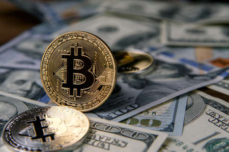 Bitcoin coins on US dollar banknotes. Cryptocurrency business concept. Exchange bitcoin cash for a dollar.の写真素材