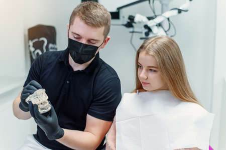 The dentist speaks with the female patient in modern clinic.の写真素材