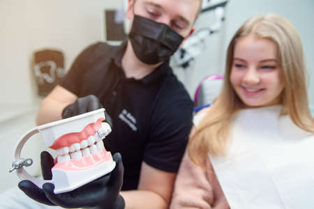 The dentist speaks with the female patient in modern clinic.の写真素材