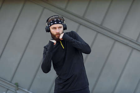 Handsome young man with headphones doing stretching and warm-up exercises before running while standing outdoors.の写真素材