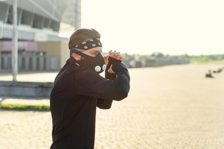 Fighter man training boxing punch on urban street. Portrait of fitness man boxing outdoor at black respirator.の写真素材