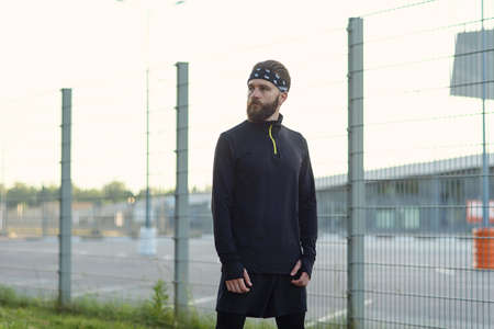 Male bearded athlete in sports uniform and bandana after hard training on the playground.の写真素材