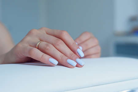Beautiful female hands with a gentle blue manicure on a stand at beauty salon.の写真素材