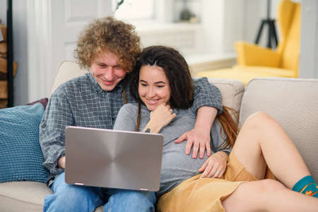 Young pregnant couple expecting a baby and looking to their family photo book.の写真素材