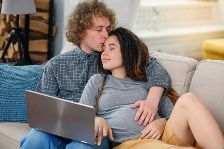 Young pregnant couple expecting a baby and looking to their family photo book.の写真素材