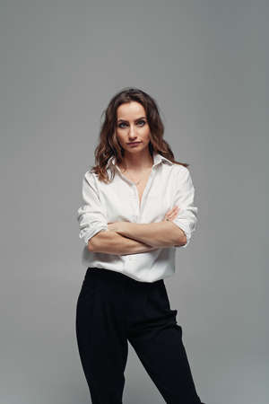 Confident pretty woman posing in black pants with a high waist and a white shirt. Business woman concept.の写真素材