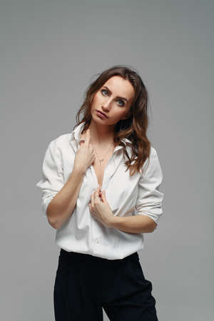 Confident pretty woman posing in black pants with a high waist and a white shirt. Business woman concept.の写真素材