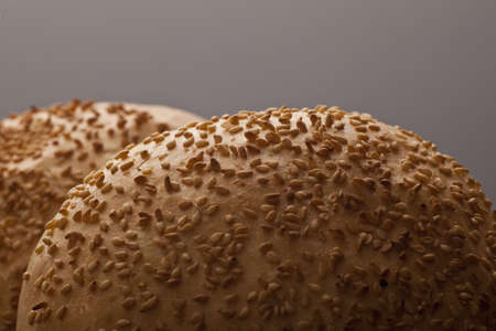 Closeup of freshly baked crisp golden sesame buns liberally covered in roast sesame seeds with...