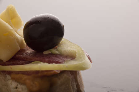 Closeup of an open sandwich topped with sliced cold meat and an olive, onion and cheese with copyspaceの写真素材