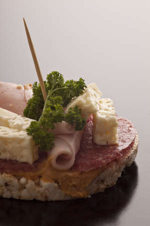 Crisp healthy low calorie rice cake with salami, ham, and feta cheese garnished with parsleyの写真素材