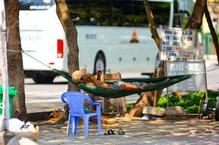 Vung Tau, Vietnam - January 29, 2018: A man lies in a hammock, smokes and looks at glasses.のeditorial素材