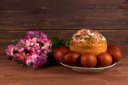 Easter cake, Easter eggs and lilac branches on a wooden table