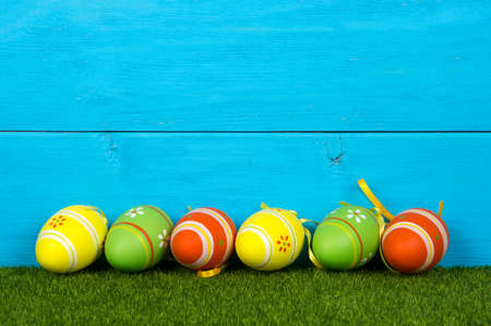 Wooden blue background with easter eggs painted in vibrant colorsの写真素材