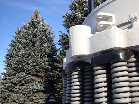 Industrial mining equipment. Huge springs. Against the backdrop of beautiful green firs and blue sky. White, gray, green and yellow.の写真素材