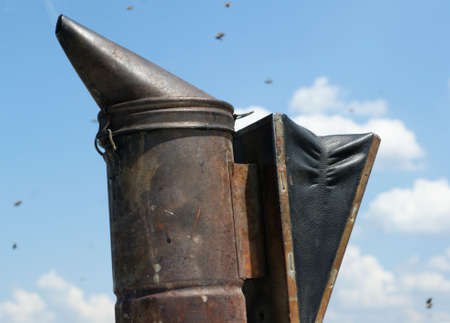 Smoke machine for beekeeping farm against the blue sky and wite clouds