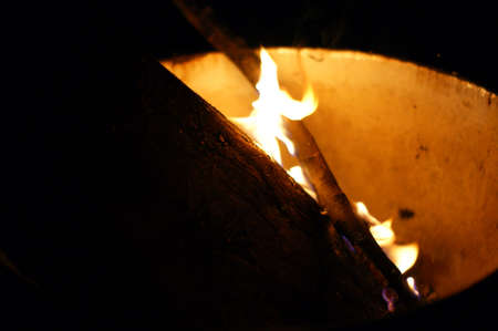 Small fire flames in a white cup at night