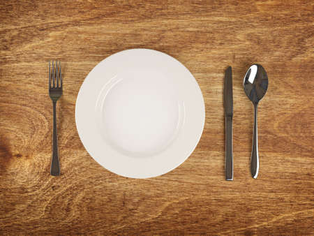 Plate and silver flatware on wooden table