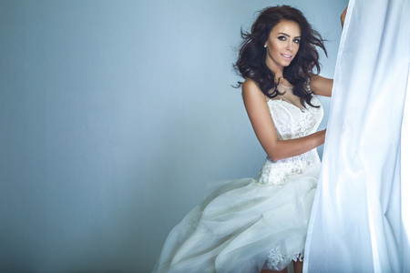 Beautiful bride posing in white fashionable dress, smiling.の写真素材