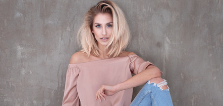 Fashionable young beautiful woman posing in jeans, looking at camera.の写真素材