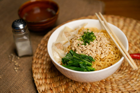 Chinese noodle soup with minced pork and vegetables in bowl on wooden tableの写真素材