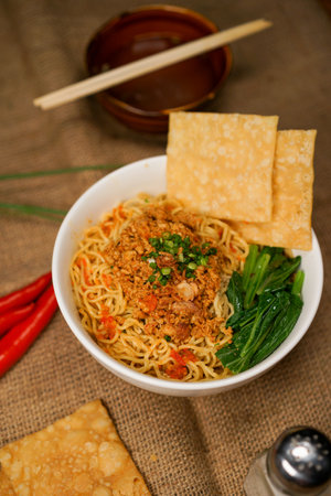 Instant noodles with minced pork in a white bowl on jute backgroundの写真素材