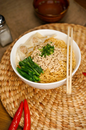 Noodles with minced pork and vegetables in a bowl on the tableの写真素材