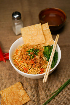 Bowl of spicy instant noodle with chopsticks on sackclothの写真素材