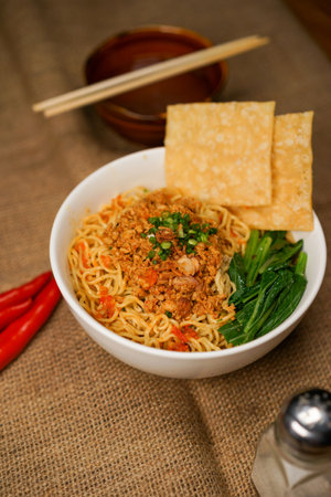 Instant noodles in bowl with chopsticks on sackcloth and wooden backgroundの写真素材