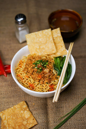Bowl of spicy instant noodle with chopsticks and crackersの写真素材