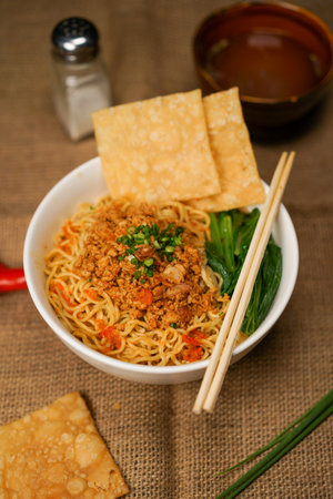 Bowl of spicy instant noodles with chopsticks on jute backgroundの写真素材