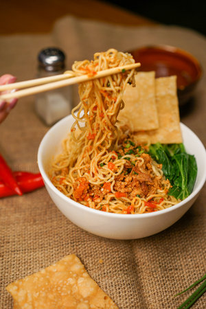 chinese noodle with pork and vegetables in white bowl with chopsticksの写真素材