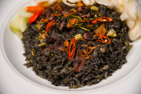 Black rice with squid and vegetables on a white plate, close up. squid fried riceの写真素材