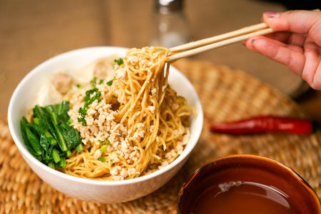Noodles with minced pork and vegetables in a bowl with chopsticksの写真素材