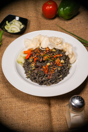 Close up of black rice with vegetables and mushrooms on a white plate. squid fried riceの写真素材