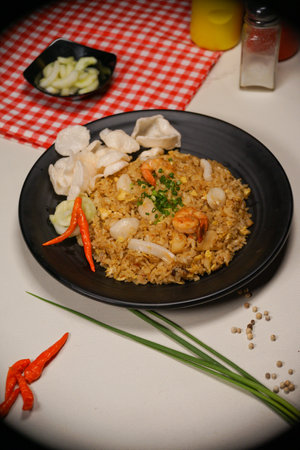 Fried rice with shrimps and squid in black plate on tableの写真素材