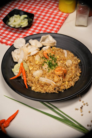 Fried rice with prawns and squid on a black plateの写真素材