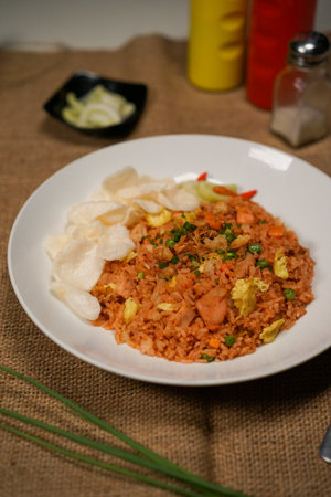 Fried rice with shrimp and vegetables in white plate on jute backgroundの写真素材
