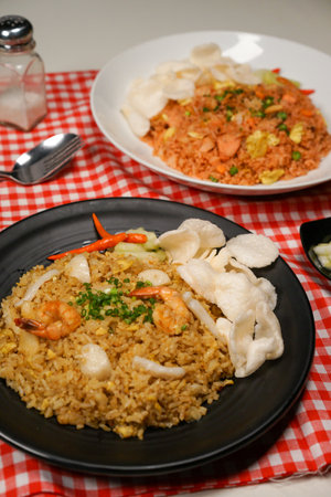 Fried rice with shrimp and vegetables in black plate on the tableの写真素材