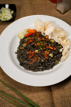 Black rice with meat and vegetables in a white plate on the table squid fried riceの写真素材