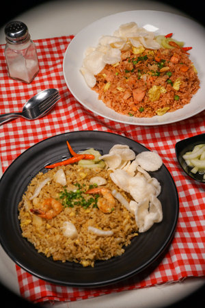 fried rice with shrimp and vegetable in black plate on red tableclothの写真素材