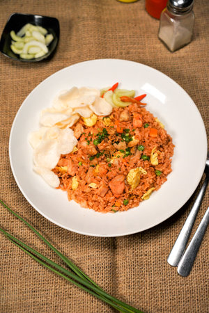 Fried rice with shrimp and vegetables in a white plate on jute backgroundの写真素材