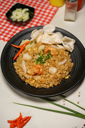 Fried rice with prawns and vegetables on a black plateの写真素材