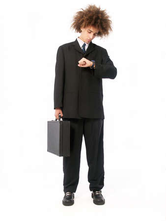 Businessman with afro hairstyle holding a suitcase while looking at watch on white backgroundの写真素材