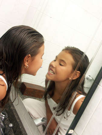 Little hispanic girl looking at her teeth in the bathroom mirrorの写真素材