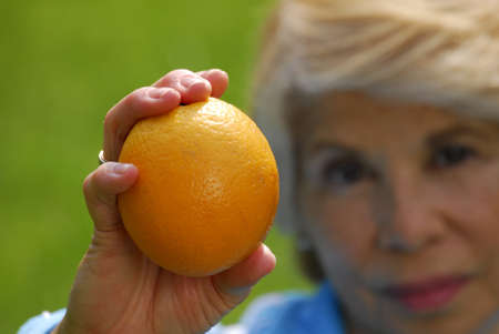Elderly woman holding an orangeの写真素材