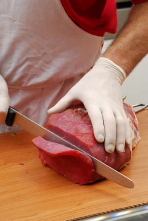 Cutting a slice of meat on a boardの写真素材