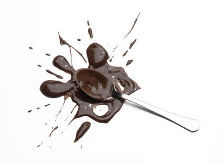 Chocolate splashed on metal spoon on white の写真素材
