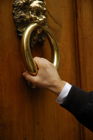 Human hand holding a brass door knocker の写真素材