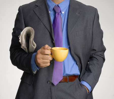 Man in suit holding newspapers and cupの写真素材
